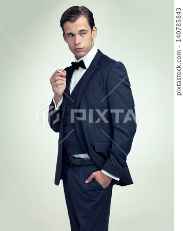 Fashion, gentleman and tuxedo with cigarette in studio for stylish, trend and habit with suit and luxury. Young person and stare with confidence for vintage, wealthy and handsome for old fashioned Fashion, gentleman and tuxedo with cigarette in studio for stylish, trend and habit with suit and luxury. Young person and stare with confidence for vintage, wealthy and handsome for old fashioned 140785843