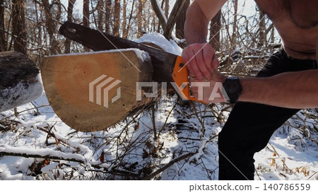 Male arm sawing a log in sunny winter forest. Strong guy working with a saw in snowy woodland. Concept of strength, masculine, energy, and harmony with nature during cold season. Slow motion Male arm sawing a log in sunny winter forest. Strong guy working with a saw in snowy woodland. Concept of strength, masculine, energy, and harmony with nature during cold season. Slow motion 140786559