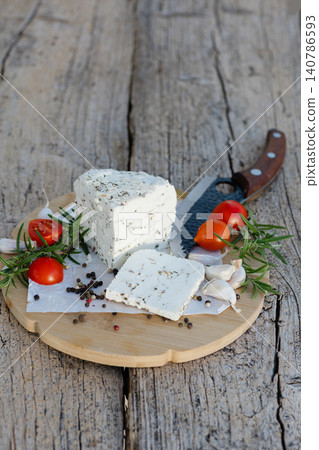 Fresh cheese with herbs served on wooden board with rosemary, tomatoes, garlic and pepper Fresh cheese with herbs served on wooden board with rosemary, tomatoes, garlic and pepper 140786593