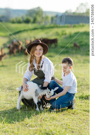 Farmers taking care of a baby goat in a field Farmers taking care of a baby goat in a field 140786606