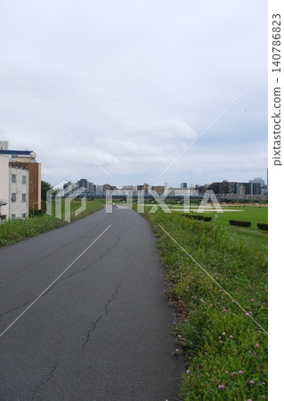 A cycling path along the Tama River, surrounded by lush greenery, through the city. A cycling path along the Tama River, surrounded by lush greenery, through the city. 140786823