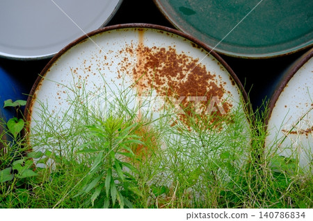 The decaying oil drums and the vibrant green of life create a striking contrast. The decaying oil drums and the vibrant green of life create a striking contrast. 140786834