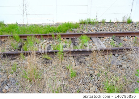 Bathed in the early summer sun, a nostalgic abandoned railway line lies dormant, overgrown with weeds. Bathed in the early summer sun, a nostalgic abandoned railway line lies dormant, overgrown with weeds. 140786850