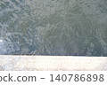 The cool, shimmering surface of the water in the early summer light contrasts sharply with the stark, inorganic concrete quay. 140786898
