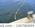 Kawasaki Port, bathed in the early summer sunlight, with floating buoys lined up on the blue waves and a tranquil pier scene. 140786899