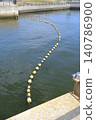 The scene of the sea off Kawasaki reflecting the early summer light, with a yellow buoy arcing across the water's surface. 140786900