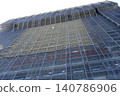 A massive construction site towering against the blue sky, with gigantic scaffolding neatly assembled. 140786906