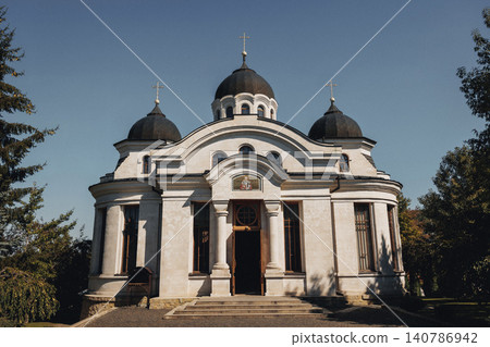 White church with black domes stands under clear blue sky White church with black domes stands under clear blue sky 140786942