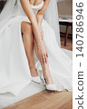Bridal legs in elegant white gown sit gracefully 140786946