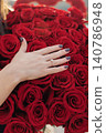 Hand rests gently on vivid red roses 140786948