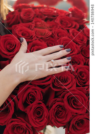 Hand rests gently on vivid red roses Hand rests gently on vivid red roses 140786948