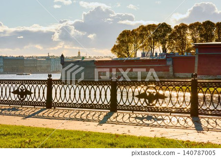 Isaac cathedral, Winter Palace, picturesque metal railings with a double-headed eagle and the crown of the Russian Empire on embankment in St. Petersburg, autumn sunset, incredible sun glare, Russia Isaac cathedral, Winter Palace, picturesque metal railings with a double-headed eagle and the crown of the Russian Empire on embankment in St. Petersburg, autumn sunset, incredible sun glare, Russia 140787005