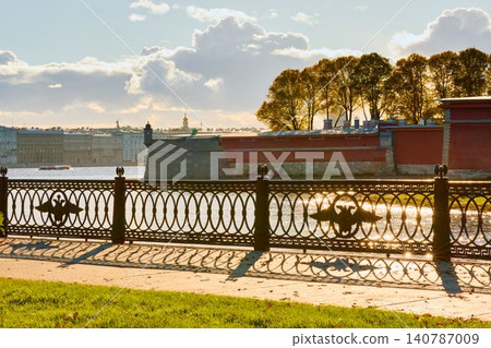 Isaac cathedral, Winter Palace, picturesque metal railings with a double-headed eagle and the crown of the Russian Empire on embankment in St. Petersburg, autumn sunset, incredible sun glare, Russia Isaac cathedral, Winter Palace, picturesque metal railings with a double-headed eagle and the crown of the Russian Empire on embankment in St. Petersburg, autumn sunset, incredible sun glare, Russia 140787009
