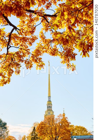 The golden spire of the Peter and Paul Fortress through yellow leaves in Saint-Petersburg - Russia at sunny autumn day, cross with angel on spire, red leaves, sunset, clear sky The golden spire of the Peter and Paul Fortress through yellow leaves in Saint-Petersburg - Russia at sunny autumn day, cross with angel on spire, red leaves, sunset, clear sky 140787030