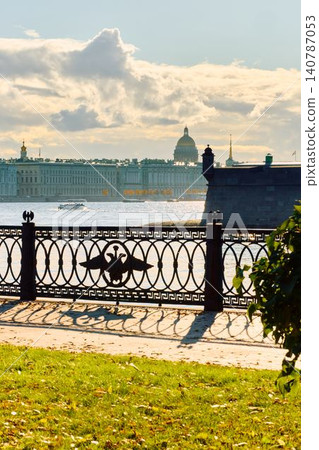 Isaac cathedral, Winter Palace, picturesque metal railings with a double-headed eagle and the crown of the Russian Empire on embankment in St. Petersburg, autumn sunset, incredible sun glare, Russia 140787053