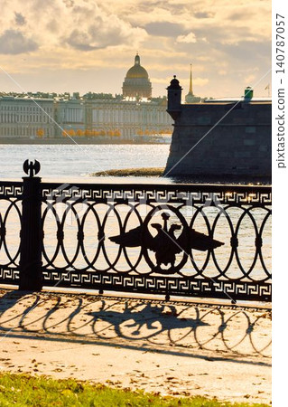 Isaac cathedral, Winter Palace, picturesque metal railings with a double-headed eagle and the crown of the Russian Empire on embankment in St. Petersburg, autumn sunset, incredible sun glare, Russia Isaac cathedral, Winter Palace, picturesque metal railings with a double-headed eagle and the crown of the Russian Empire on embankment in St. Petersburg, autumn sunset, incredible sun glare, Russia 140787057