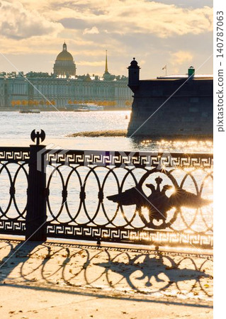Isaac cathedral, Winter Palace, picturesque metal railings with a double-headed eagle and the crown of the Russian Empire on embankment in St. Petersburg, autumn sunset, incredible sun glare, Russia 140787063