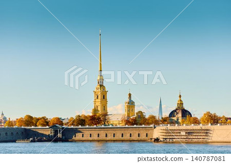 The golden spire of the Peter and Paul Fortress through yellow leaves in Saint-Petersburg - Russia at sunny autumn day, cross with angel on spire, red leaves, sunset, clear sky 140787081