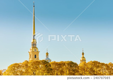 The golden spire of the Peter and Paul Fortress through yellow leaves in Saint-Petersburg - Russia at sunny autumn day, cross with angel on spire, red leaves, sunset, clear sky 140787085