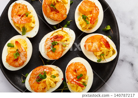 Boiled eggs stuffed with yolk and seasoned with mayonnaise, stuffed eggs with shrimp, on a black plate, selective focus, close-up, no people, 140787217