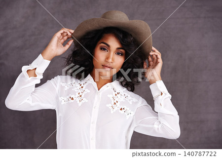 Portrait, studio and woman with cowboy fashion, confidence and relax with girl in stetson hat. Rodeo, western style and face Mexican model with cowgirl culture, wild west clothes and grey background 140787722