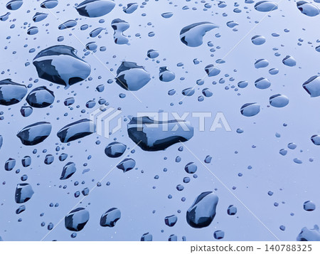 Raindrops on a car body reflecting the blue sky; a background texture material with a beautiful water droplet texture. Raindrops on a car body reflecting the blue sky; a background texture material with a beautiful water droplet texture. 140788325