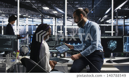 System administrator and employee programs on a computer workstation in a server hub with generative AI assistance. 140788549