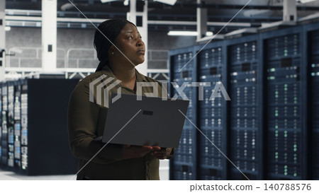 Data center engineer uses laptop in a server farm to plan disaster recovery and strengthen data protection. 140788576