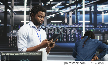 Data center technician uses a tablet with node tree programming to optimize resource allocation and analytics. Data center technician uses a tablet with node tree programming to optimize resource allocation and analytics. 140788589
