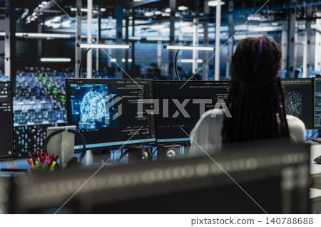 Female technician uses a desktop computer in a data center to manage AI systems and optimize server infrastructure. 140788688