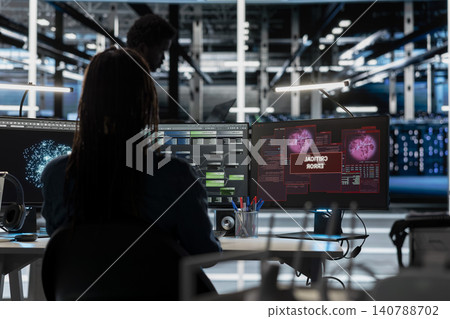 Concerned IT employee reviews warning messages in a data center while troubleshooting errors affecting equipment performance. Concerned IT employee reviews warning messages in a data center while troubleshooting errors affecting equipment performance. 140788702