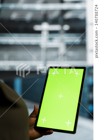 System administrator uses a green screen tablet in a sustainable data center to apply energy efficient solutions and reduce carbon footprint. System administrator uses a green screen tablet in a sustainable data center to apply energy efficient solutions and reduce carbon footprint. 140788724