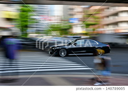 A panning shot of a black luxury car driving during the morning commute. A panning shot of a black luxury car driving during the morning commute. 140789005