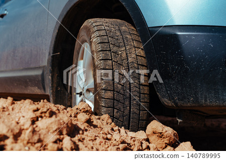 Car wheel standing offroad on stones and sand close-up view Car wheel standing offroad on stones and sand close-up view 140789995