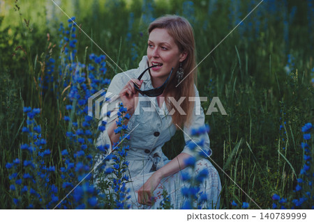 Portrait of young woman with sunglasses in a flower meadow Portrait of young woman with sunglasses in a flower meadow 140789999