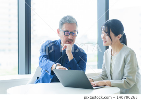 Middle-aged businessmen teaching women how to use computers Middle-aged businessmen teaching women how to use computers 140790263