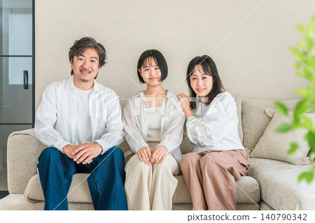 父母和孩子坐在家裡的客廳沙發上。 父母和孩子坐在家裡的客廳沙發上。 140790342