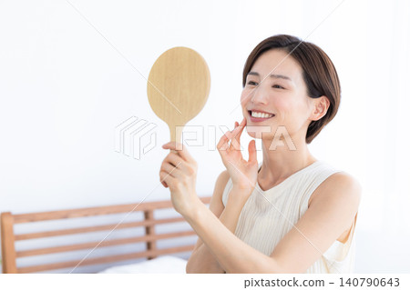 Beauty image: A woman checking the condition of her skin in a hand mirror. Beauty image: A woman checking the condition of her skin in a hand mirror. 140790643