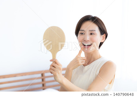 Beauty image: Woman looking at her teeth in a hand mirror Beauty image: Woman looking at her teeth in a hand mirror 140790648