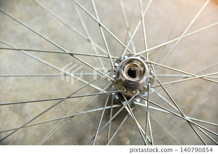 Close-up top view of a shiny metallic bicycle wheel hub with steel spokes radiating outwards, abstract mechanical and transportation concept. 140790854
