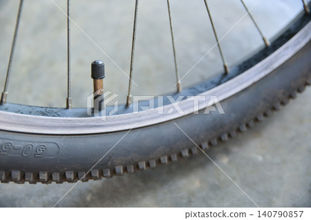 air valve with a black cap on a mountain bike tire and rim, focusing on bicycle maintenance. air valve with a black cap on a mountain bike tire and rim, focusing on bicycle maintenance. 140790857