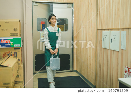 一位二十多歲的超市女員工微笑著從後屋走出來。 一位二十多歲的超市女員工微笑著從後屋走出來。 140791209