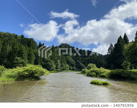 寧靜的池塘景色,周圍環繞著森林和湛藍的天空。 寧靜的池塘景色,周圍環繞著森林和湛藍的天空。 140791956