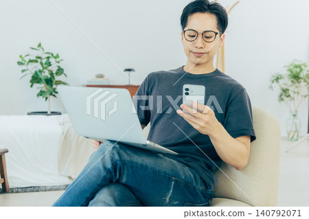 Man sitting on sofa and using smartphone 140792071