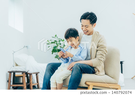 A young family looking at a smartphone in the living room A young family looking at a smartphone in the living room 140792074