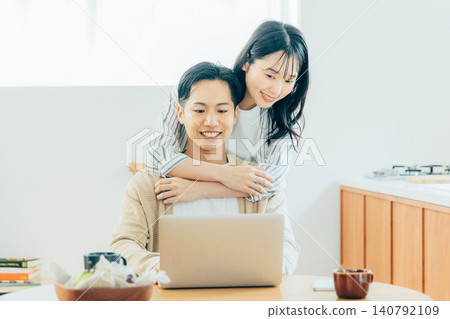 Young couple looking at a computer in the living room Young couple looking at a computer in the living room 140792109