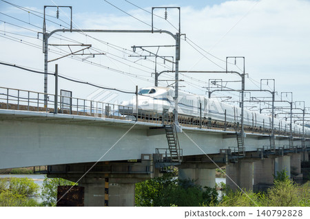 東海道新幹線運行在橫跨河流的高架橋上。 東海道新幹線運行在橫跨河流的高架橋上。 140792828