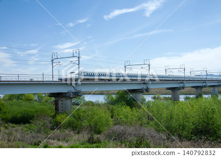 東海道新幹線運行在橫跨河流的高架橋上。 東海道新幹線運行在橫跨河流的高架橋上。 140792832