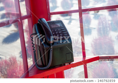 A red telephone booth and a retro public telephone. A red telephone booth and a retro public telephone. 140792859