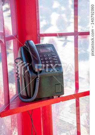 A red telephone booth and a retro public telephone. A red telephone booth and a retro public telephone. 140792860